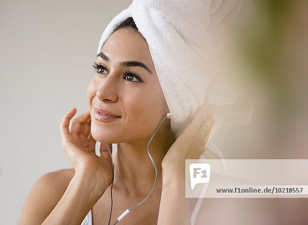 Woman with hair in towel listening to headphones