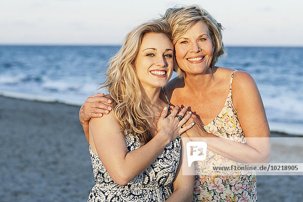 Caucasian mother and daughter smiling on beach