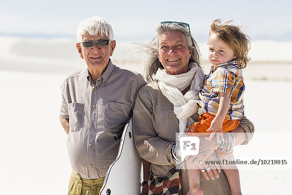 Caucasian grandparents and grandson smiling in desert