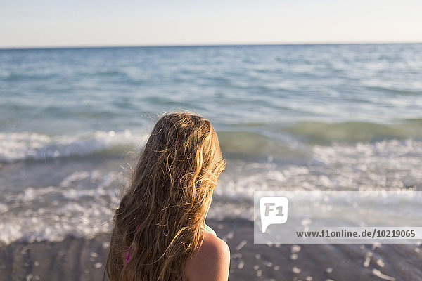 Caucasian girl watching waves on beach