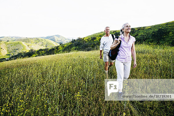 Caucasian couple hiking on hillside