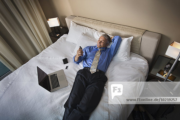 Handy benutzen Europäer Geschäftsmann Bett Hotel
