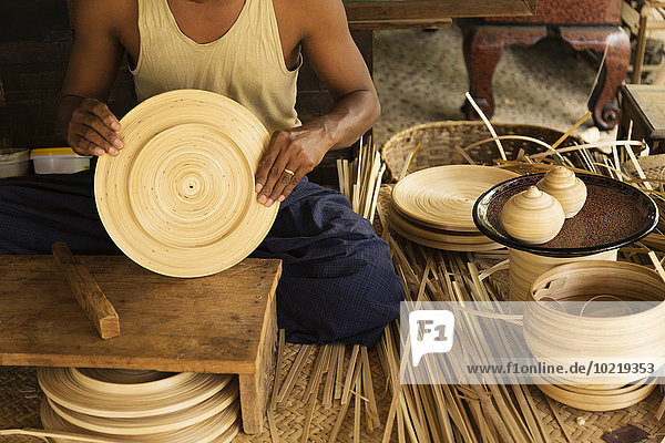 Asian artisan weaving traditional baskets in workshop