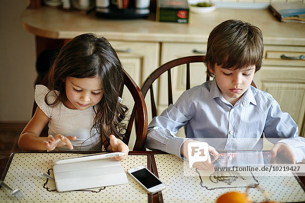 Caucasian brother and sister using digital tablets