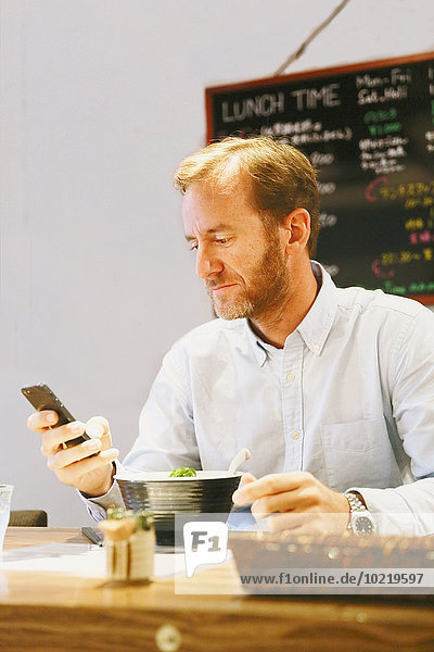 Caucasian man with smartphone in a ramen restaurant
