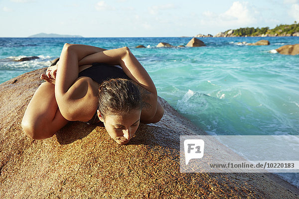 Seychellen Frau beim Yoga auf einem Felsen