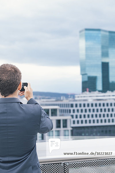 Young man with suit taking photos at business building
