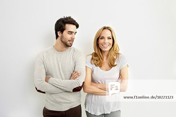 Portrait of smiling woman standing besides young man watching her in front of white background