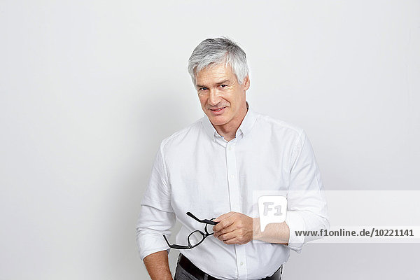 Portrait of handsome mature man holding glasses in his hand