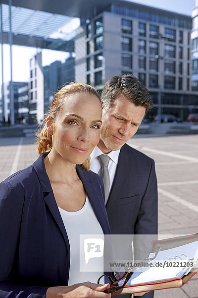 Deutschland  Stuttgart  Porträt einer lächelnden jungen Geschäftsfrau mit ihrer Kollegin im Hintergrund