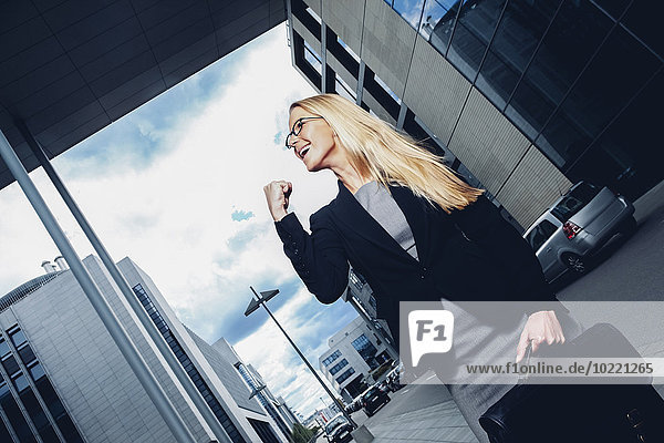 Businesswoman with clenched fist outside office building
