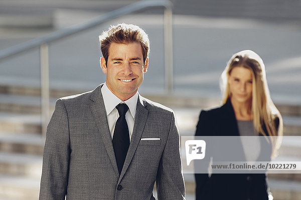 Lächelnder Geschäftsmann mit Geschäftsfrau im Hintergrund