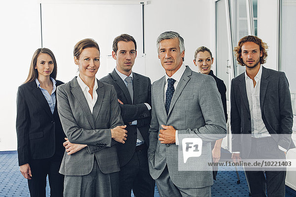 Gruppe von Geschäftsleuten  die im Büro stehen  mit Blick auf die Kamera