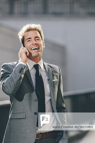 Lächelnder Geschäftsmann beim Telefonieren im Freien