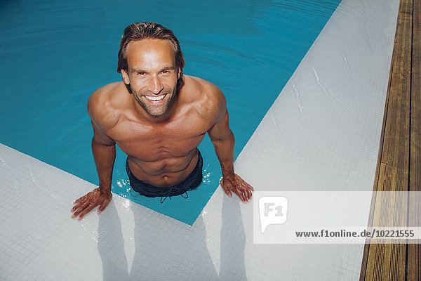 Portrait of smiling man getting out of swimming pool