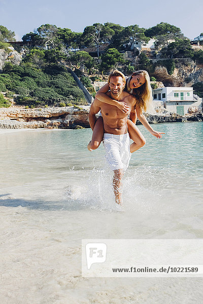 Spanien  Mallorca  Mann huckepack mit seiner Freundin am Meer