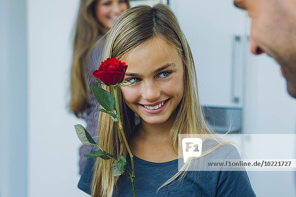 Lächelndes Mädchen mit Eltern  die Rose halten