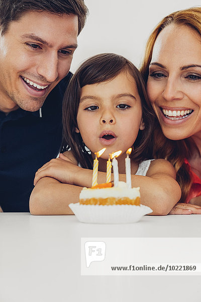 Familie mit Tochter feiert Geburtstag mit Kerzen auf Kuchen