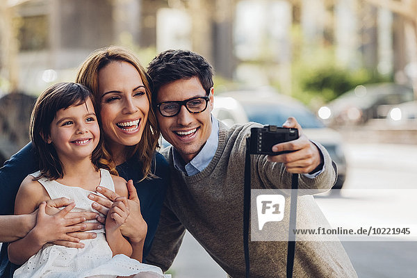 Mann im Freien  der einen Selfie seiner Familie mit Digitalkamera nimmt