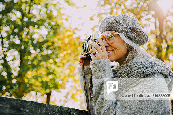 Frau fotografiert mit einer alten Kamera in einem herbstlichen Park