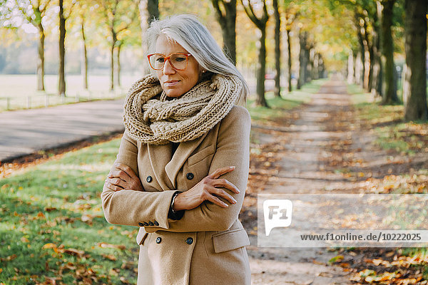 Porträt einer Frau mit Schal und Brille beim Spaziergang im herbstlichen Park