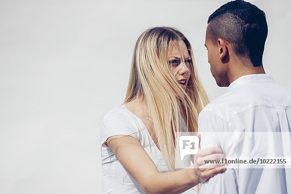 Portrait of angry young woman face to face with her boyfriend in front of white background