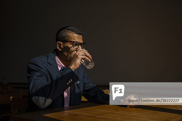 Young man sitting in cafe drinking water
