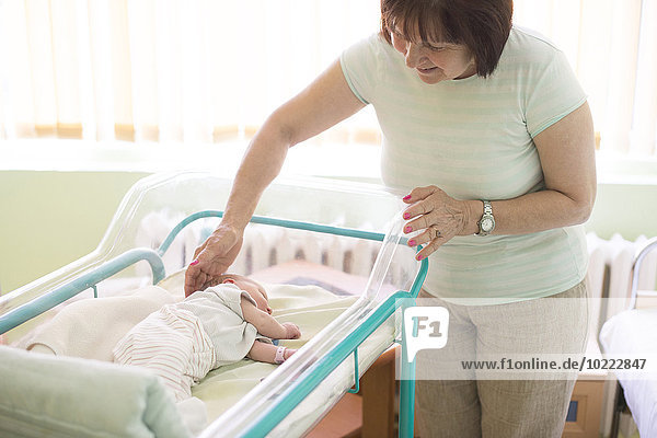 Seniorin beobachtet ihre neugeborene Enkelin im Krankenhaus