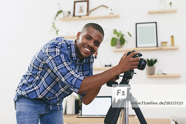 Porträt eines lächelnden jungen Mannes bei der Arbeit in seinem Fotostudio