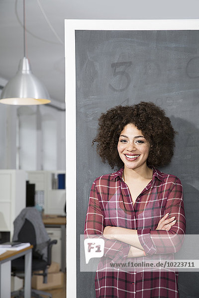 Lächelnde junge Frau an der Tafel im Büro stehend