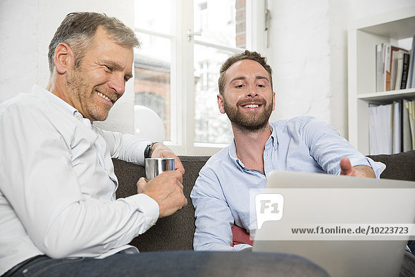 Two smiling businessmen sharing laptop