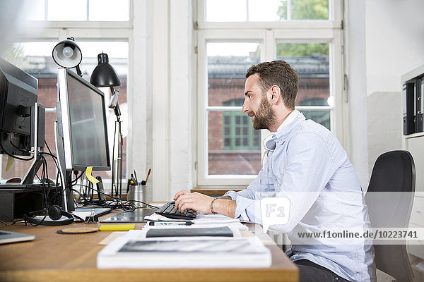 Junger Mann im Büro arbeitet am Computer