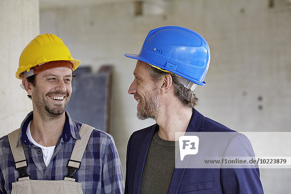 Lächelnder Bauarbeiter und Architekt auf der Baustelle