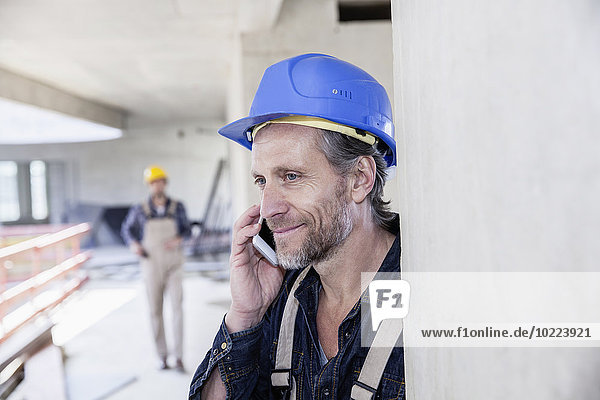 Lächelnder Arbeiter auf der Baustelle am Handy