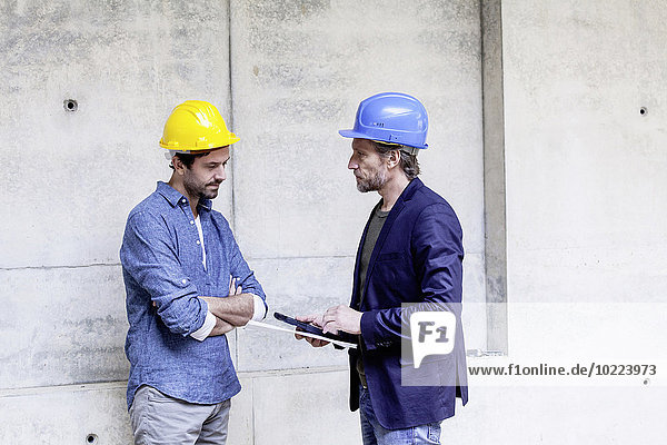 Two men on construction site wearing hard hats