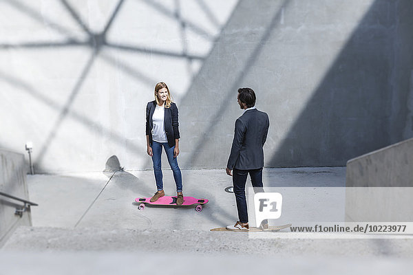 Zwei Geschäftsleute auf Skateboards in moderner Architektur