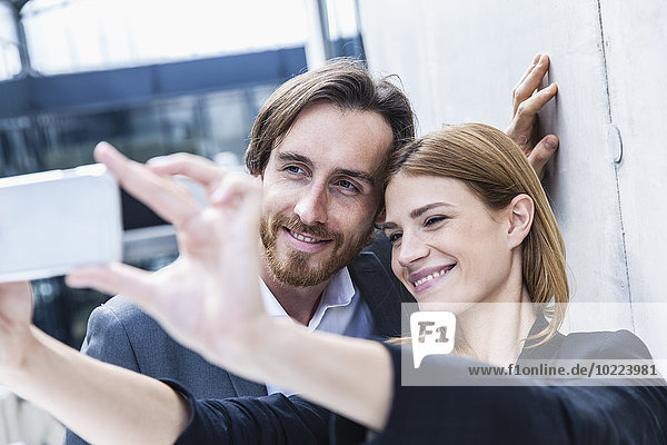 Portrait of two business people taking a selfie with smartphone
