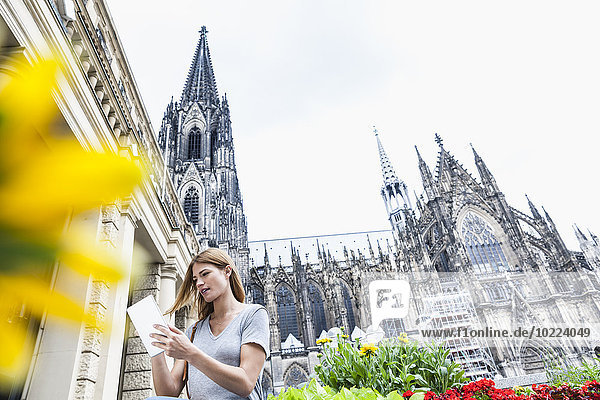 Deutschland  Köln  junge Frau mit digitalem Tablett vor dem Kölner Dom