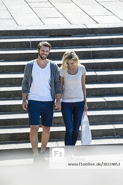 Deutschland  Köln  glückliches junges Paar  das die Treppe hinuntergeht