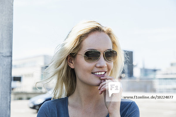 Deutschland  Köln  Porträt einer lächelnden jungen Frau mit Sonnenbrille