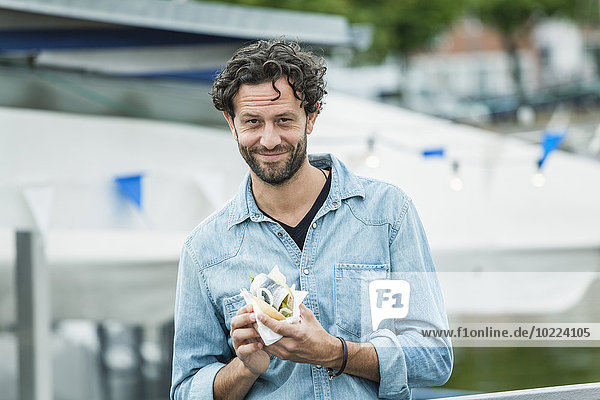Smiling man holding a fish sandwich