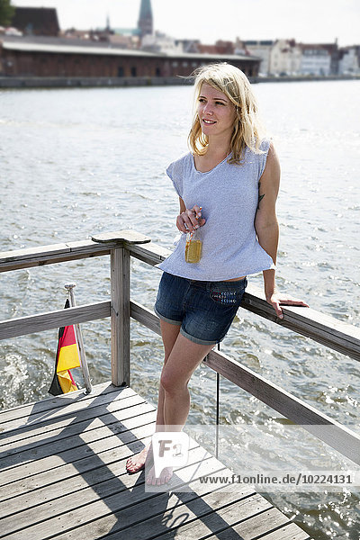 Lächelnde junge Frau mit Bierflasche auf einem Hausboot