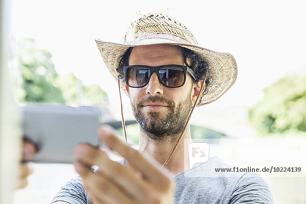 Mann mit Strohhut und Sonnenbrille mit einem Selfie