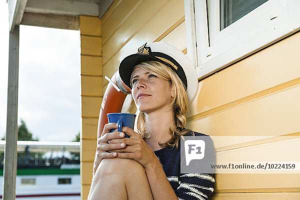 Entlassene Frau auf einem Hausboot mit Kaffeetasse