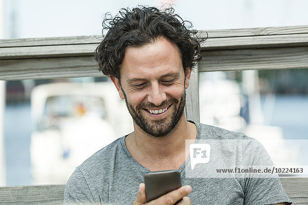 Lächelnder Mann im Freien mit Blick auf das Handy