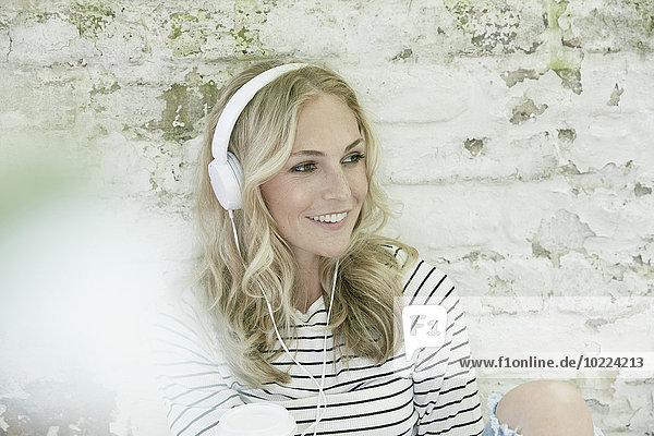 Portrait einer lächelnden blonden Frau mit Kopfhörer