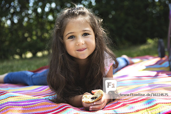Porträt eines lächelnden kleinen Mädchens auf einer Decke liegend