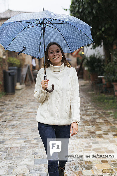Italien  San Gimignano  Porträt einer lächelnden jungen Frau mit Regenschirm