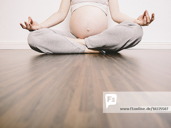 Schwangere Frau in Yogastellung auf Holzboden