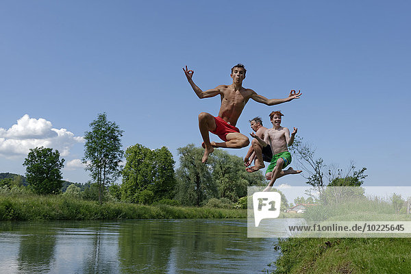 Germany  Bavaria  two teenage boys and man jumping into River Loisach